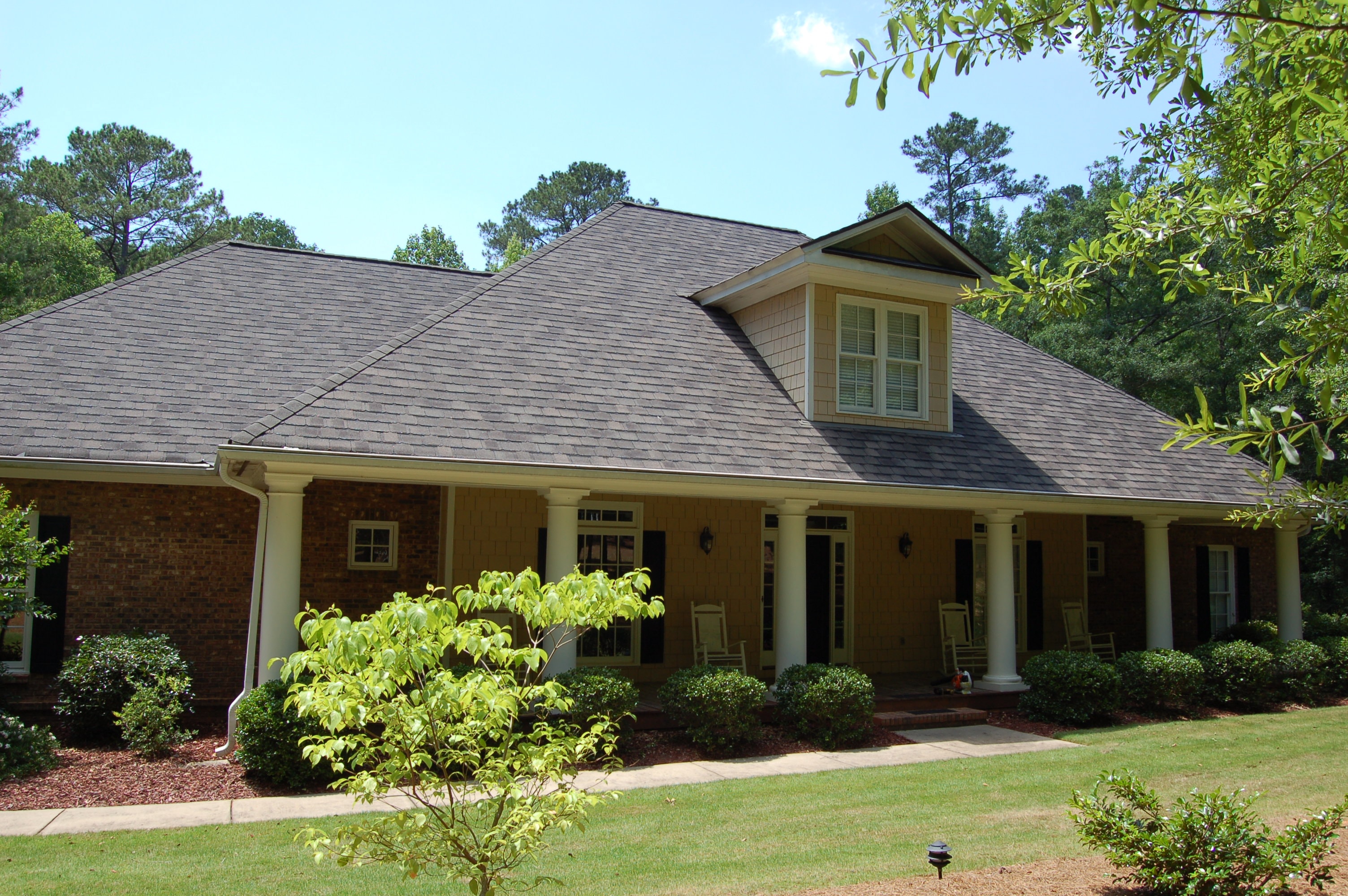 Brick home with columned porch after roof replacement