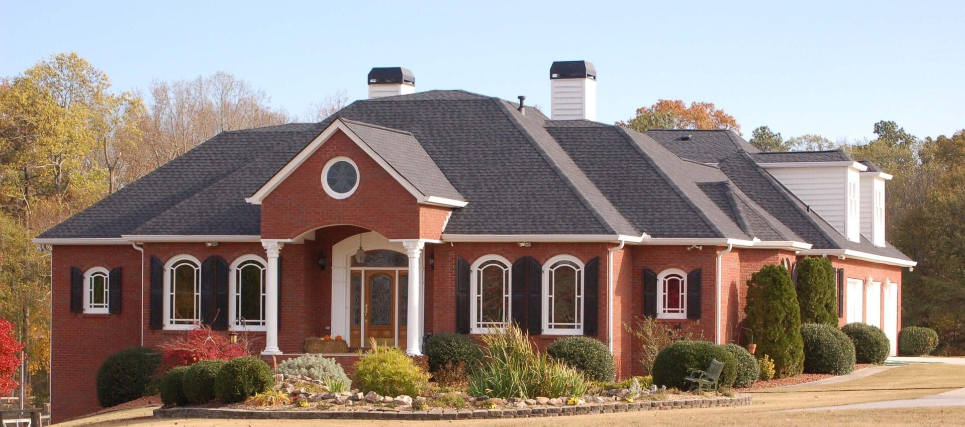 A red brick house with black roof and white trim.
