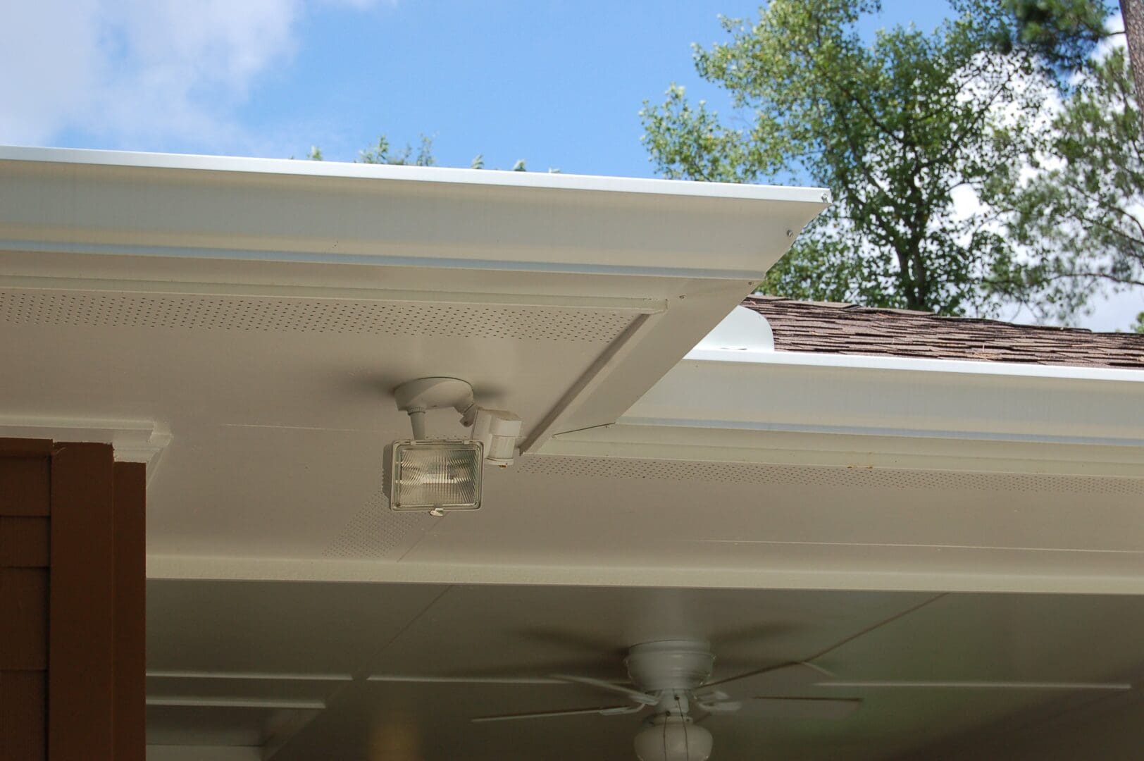 A ceiling fan is hanging from the side of a house.