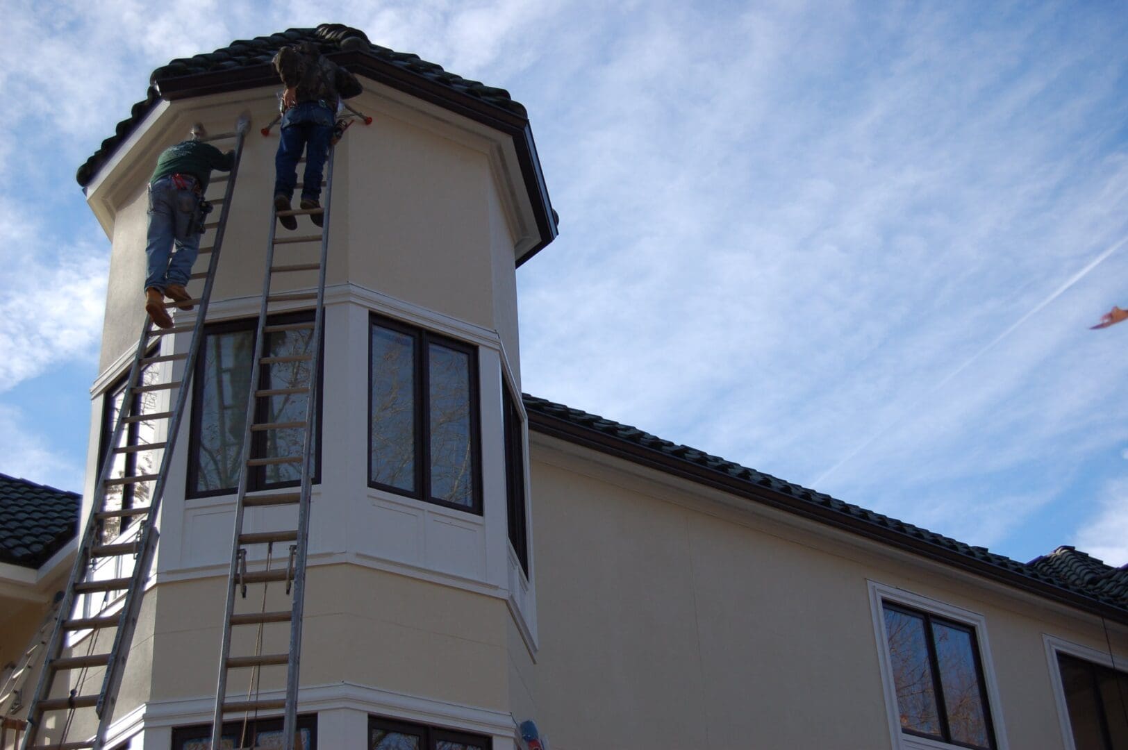 A man on a ladder painting the side of a building.